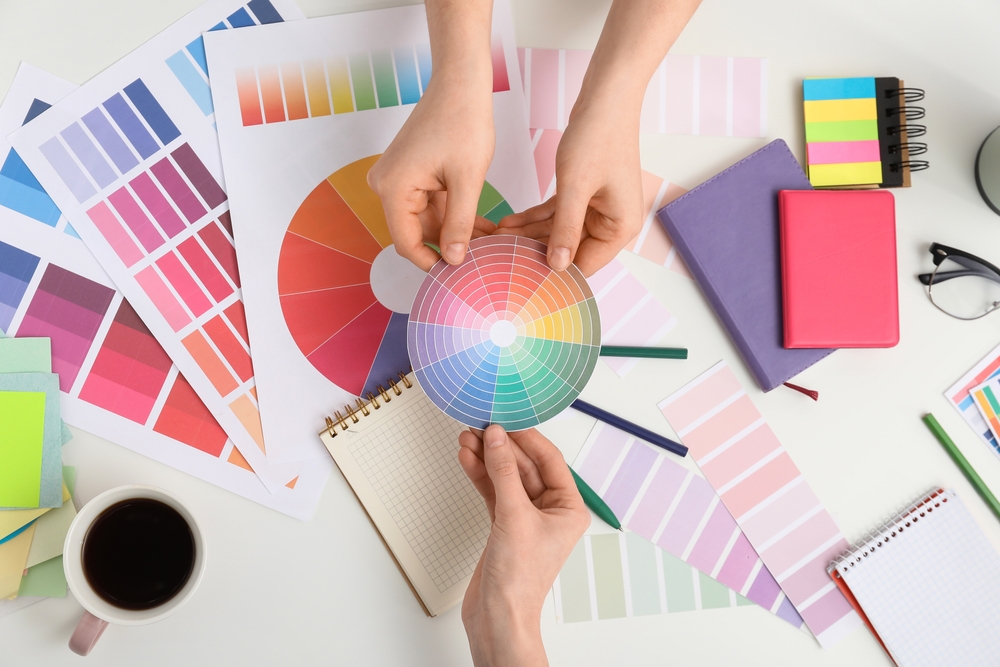 female,graphic,designers,holding,color,palette,on,white,background,,top